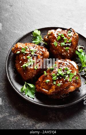 Süß und würzig Honig gegrillte Hähnchen Schenkel auf die Platte über der dunklen Stein Hintergrund. Lecker essen im asiatischen Stil. Stockfoto