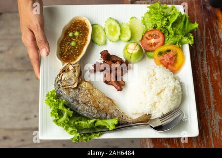 Reis, Chili Sauce, Fisch und Schweinefleisch gebraten mit Gemüse auf einem weißen Teller Stockfoto