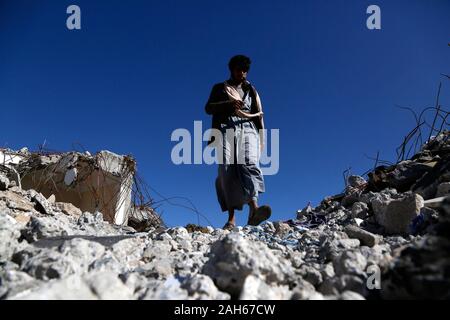 (191225) - DHAMAR (Jemen), Dez. 25, 2019 (Xinhua) - ein Mann geht auf Trümmer von Gebäuden in Luftangriffe in Dhamar Provinz zerstört, Jemen, Dez. 25, 2019. Die andauernden Kämpfe zwischen den beiden verfeindeten Rivalen mit täglichen Saudi-geführten Luftangriffe Jemen in Chaos und Gewalt gestürzt. Drei Viertel der Bevölkerung, das sind mehr als 22 Millionen Menschen benötigen dringend irgendeine Form der humanitären Hilfe, einschließlich der 8,4 Millionen, die kämpfen, um ihre nächste Mahlzeit zu finden. (Foto von Mohammed Mohammed/Xinhua) Stockfoto