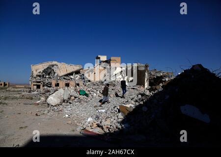 (191225) - DHAMAR (Jemen), Dez. 25, 2019 (Xinhua) - Leute gehen auf Trümmer von Gebäuden in Luftangriffe in Dhamar Provinz zerstört, Jemen, Dez. 25, 2019. Die andauernden Kämpfe zwischen den beiden verfeindeten Rivalen mit täglichen Saudi-geführten Luftangriffe Jemen in Chaos und Gewalt gestürzt. Drei Viertel der Bevölkerung, das sind mehr als 22 Millionen Menschen benötigen dringend irgendeine Form der humanitären Hilfe, einschließlich der 8,4 Millionen, die kämpfen, um ihre nächste Mahlzeit zu finden. (Foto von Mohammed Mohammed/Xinhua) Stockfoto