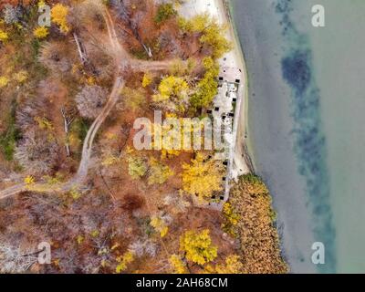 Drone Bild von heruntergekommenen verlassenen konkrete Lastkahn auf River Bank im Herbst Verfallende neben einem Fluss. Stockfoto