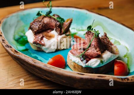 Bruschetta mit Roastbeef auf Zwiebel Brot medium gebratenes Roastbeef und saurer Sahne-Sauce. Leckere Snacks, Sandwiches. Stockfoto