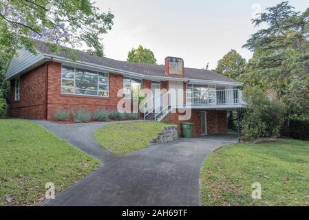 Einer Ecke der 60er Jahre nach dem Zweiten Weltkrieg moderne Australische, Single Level home mit einem zentralen Kamin gebaut, doppelte Wände aus Backstein und terrakottafarbenen Dachziegeln Stockfoto