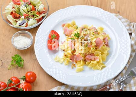 Österreichische Schinken Nudeln, so genannte schinkenfleckerl, und einem Beilagensalat mit Steirisches Kürbiskernöl Stockfoto