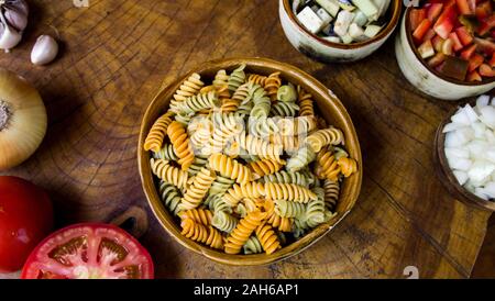 Frische Zutaten zum Kochen: Pasta, Tomaten, Paprika, Zwiebeln, Auberginen und Knoblauch über alten Holztisch Hintergrund. Ansicht von oben. Stockfoto