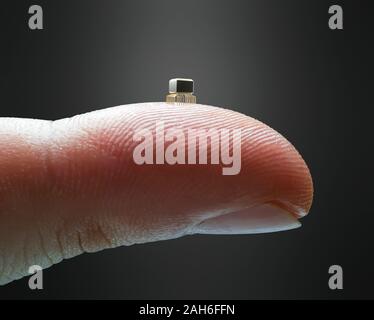 Winzigen Mikrochip auf der Fingerspitze. Finger mit einem miniaturisierten Mikrochips. Konzept und Entwicklung der Informatik. Stockfoto