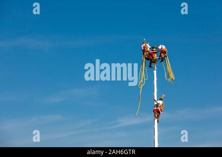 Teotihuacan, Mexiko - 25 November 2019: Zwei Männer in Trachten sitzen auf einer Säule. Ein anderes geht, um die Säule. Fertig Stockfoto