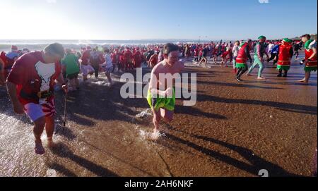 Fast 1.200 Personen nahmen an der jährlichen Weihnachten Macmillan Pflege Weiße Weihnachten Dip 25/12/2019. Menschen in Fancy Dress und auf einem hellen, sonnigen Morgen lief in das Meer auf Boscombe Meer. Geld für Macmillian Pflege lokal die Palliativstation in Christchurch, dieses Ereignis im Laufe der Jahre zugenommen hat. Rund eine Viertel Million wurde seit den Ereignissen Anfänge angehoben. Stockfoto