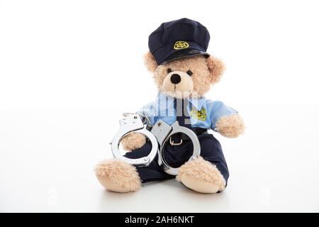 Polizei und Verhaftung Konzept. Niedlichen Teddybären in Polizeioffizier einheitliche und Handschellen vor weißem Hintergrund Stockfoto