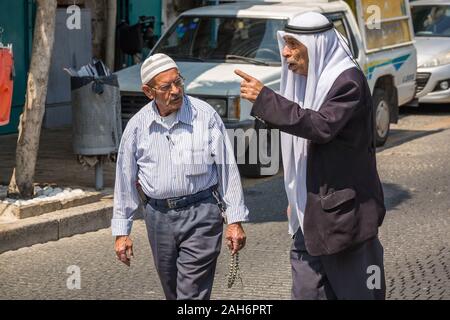 Akko, Israel - 15 April 2018: Zwei ältere Muslime sind zu Fuß die Straße in traditioneller Kleidung. Stockfoto