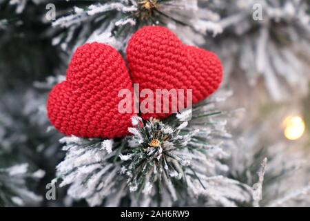 Weihnachten Herz, Tag Valentinstag Karte, zwei Rote gestrickt, Symbole der Liebe im Schnee auf tannenzweigen. Hintergrund für romantische Ereignis, neues Jahr Stockfoto