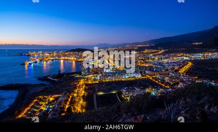 Spanien, Teneriffa, Verloren christianos tourist resort Skyline der Stadt in magisch beleuchtete Atmosphäre nach Sonnenuntergang, Luftbild oben Stockfoto