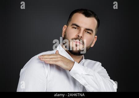 Bärtiger Mann im Hemd Bürste Staub aus Schulter auf schwarzem Hintergrund. Alles muss perfekt sein. Stockfoto