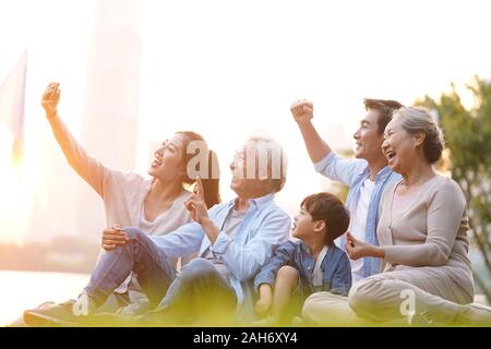 Drei generation gerne asiatische Familie sitzt auf Gras, eine selfie mit Handy draußen im Park Stockfoto