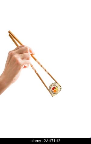 Junge weibliche Hand mit Stäbchen aus Holz mit einem frisch zubereiteten veganen Maki Sushi Roll-Hintergrundbeleuchtung, Ausschnitt auf weißem Hintergrund, kopieren Raum Stockfoto
