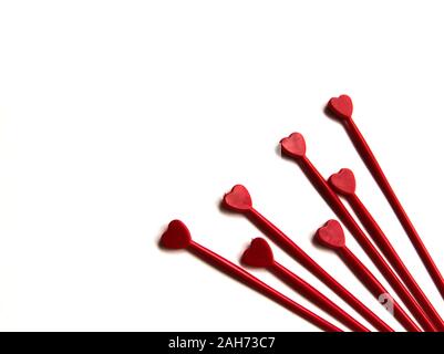 Aus rotem Kunststoff sticks für Kanapees mit Herz auf weißem Hintergrund isoliert. Dekorative Essstäbchen. Stockfoto