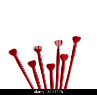 Aus rotem Kunststoff sticks für Kanapees mit Herz auf weißem Hintergrund isoliert. Dekorative Essstäbchen. Stockfoto