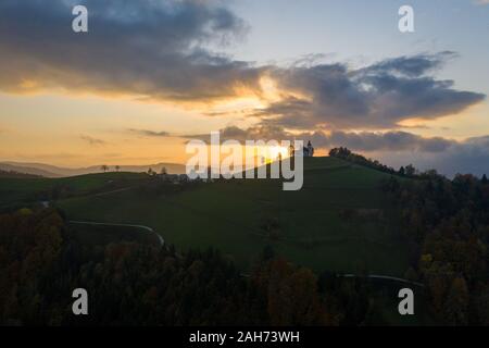 Luftaufnahme der Hügel, bunte Wälder und dem Sv Sobota Kirche. Slowenien Sonnenuntergang im Herbst Stockfoto