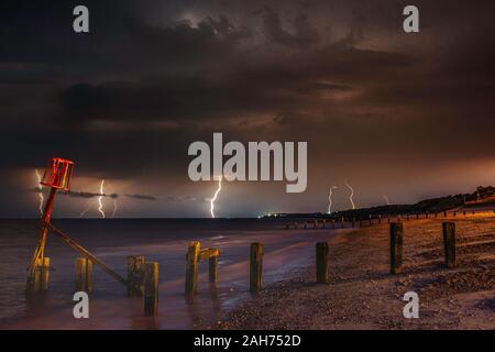 Blitzeinschläge auf einem Küstenabschnitt von Wasser, gut mit Vordergrund Interesse ausgesetzt Stockfoto