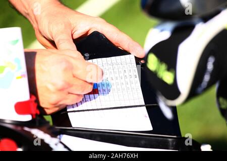 Golfspieler, die Kerben im Spielprotokoll mit Händen Stockfoto