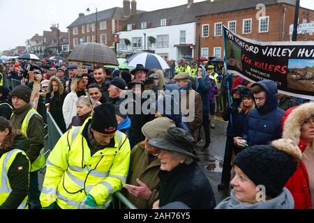 Tenterden, Kent, Großbritannien. 26. Dezember, 2019. Die jährlichen Boxing Day treffen der Ashford Tal Tickham Jagd findet im Zentrum von Tenterden in Kent. Hunde und Pferde versammeln sich in der 'Vine Inn Pub bei 11, bevor Sie die High Street zu einem verpackten Publikum bin. Das Wetter ist nass und regnerisch Regen. Fuchsjagd Demonstranten jeer die Fuchsjagd, wie sie weg. © Paul Lawrenson 2019, Foto: Paul Lawrenson/Alamy leben Nachrichten Stockfoto