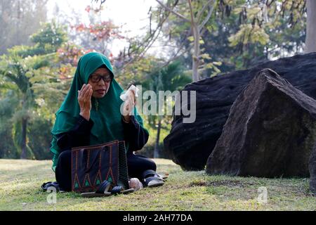 (191226) - Aceh, Dez. 26, 2019 (Xinhua) - Eine indonesische Frau betet Catalysts Lheue Masse Friedhof, wo der Tsunami 2004 tsunami Opfer während der Feierlichkeiten zum 15. Jahrestag der verheerenden Tsunami begraben sind, in Aceh, Indonesien, 26.12.2019. Mehr als 120.000 Menschen wurden in der Provinz Aceh durch ein fast 30 Meter hoher tsunami durch eine megathrust Erdbeben, die Unterwasserwelt vor der Küste von Sumatra Insel am Dez. 26, 2004 Struck ausgelöst getötet. Jedes Jahr, das Aceh Administration enthält eine Funktion zum Gedenken an das Erdbeben 2004 und Tsunami. Gehen mit'-Funktion: 15 Jahre auf, Indone Stockfoto