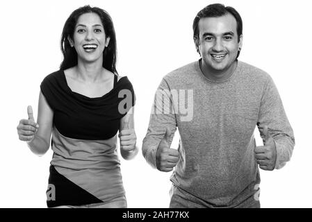Studio shot von Happy persischen Paar lächelnd und geben Daumen bis in Schwarz und Weiß Stockfoto