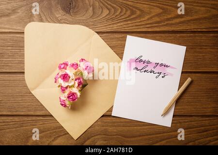 Mockup Brief und Umschlag auf Holz mit Liebe sie immer Text und Kraft der Blumen. Mock up für elegantes Design. Flach Tag der Ansicht von oben Valentine backgroun Stockfoto