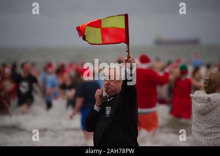 Tynemouth, England, 26. Dezember 2019. Als Linienrichter verbindet die Teilnehmer in der Nordsee während der Boxing Day Dip, ist eine jährliche Veranstaltung, die von der Nordsee ehrenamtliche Rettungsschwimmer organisiert auf dem Longsands Tynemouth. Stockfoto