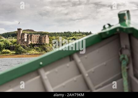 Im Vordergrund das grüne und graue Vordergrunds eines Holzbootes, in der Ferne das Ufer einer schottischen Insel mit einer alten Burg Stockfoto