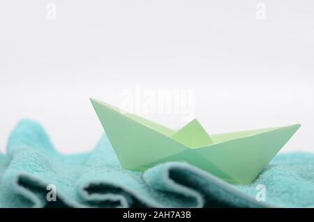 Papier Schiff segelt auf wollstoff Wellen, hand Papier Boot auf gewebe Wellen gestaltete. Stockfoto