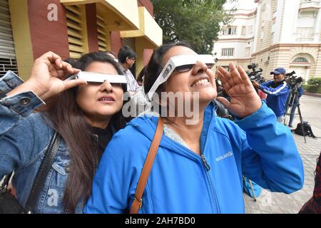 Kolkata, Indien. 26 Dez, 2019. Die ringförmige Sonnenfinsternis wird als partielle Sonnenfinsternis in Kalkutta von Frauen durch Solar Anzeigen Film beobachtet. (Foto durch Biswarup Ganguly/Pacific Press) Quelle: Pacific Press Agency/Alamy leben Nachrichten Stockfoto