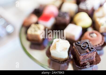 Nahaufnahme eines silbernen Tabletts mit Gebäck, mit einem Brownie im Vordergrund, vor einem Bokeh Hintergrund Stockfoto