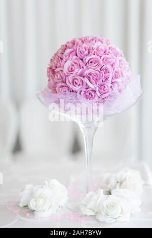 Nahaufnahme einer Hochzeit Dekoration bestehend aus einem riesigen Kelch gefüllt mit einem Bouquet von rosa Rosen gegen ein Weißer Bokeh-Hintergrund Stockfoto