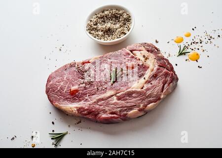 Frisches rohes Fleisch ohne Knochen ribeye Steak mit Spice Rub und Kräuter diagonal auf weißem Hintergrund Stockfoto