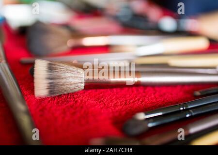 Nahaufnahme eines Sets von Make-up-Bürsten liegen Auf einem roten Tuch vor einem Bokeh-Hintergrund Stockfoto