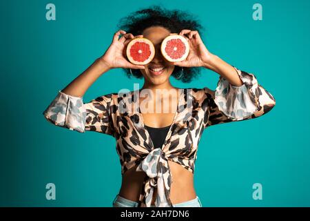 Ziemlich afrikanische Frau in Leopard Print Top mit zwei halben Juicy Grapefruit Stockfoto