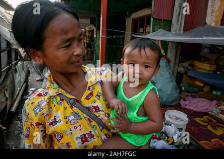 Eine asiatische Frau, die auf der Strasse leben Wer verdient ein Leben von scavenging Dosen und Kartons hält ihren kleinen Sohn bei ihr Unterschlupf in Kampong Cham, Kambodscha Stockfoto