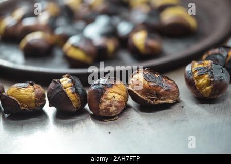 Nahaufnahme von gerösteten Kastanien für den Verkauf auf der Straße im Winter. Street Food Konzept. Stockfoto