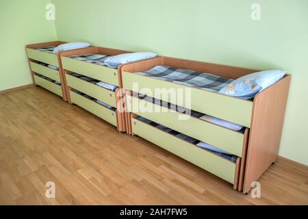 Viele kleine Betten mit frischer Bettwäsche in der Kindertagesstätte Vorschule leere Schlafzimmer Innenraum für komfortable Mittagsschlaf der Kinder. Stockfoto