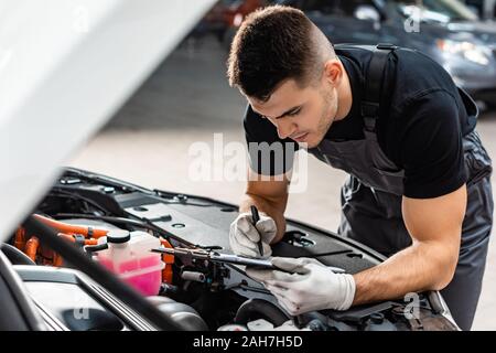 Selektiver Fokus der Mechaniker schreiben auf Zwischenablage während der Inspektion auto Motorraum Stockfoto