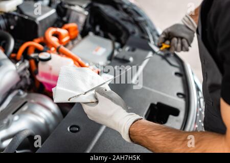 7/8-Ansicht von mechanischen Ölmessstab mit Lappen abwischen nahe den Motorraum Stockfoto