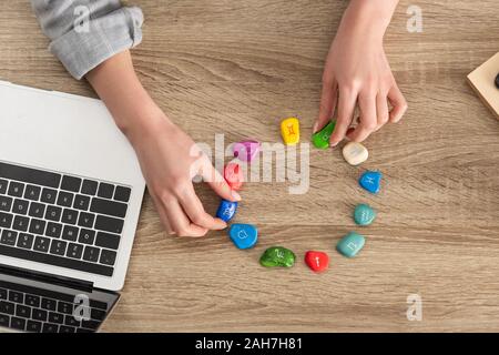 7/8-Ansicht von Frau Steine Holding mit Sternzeichen neben Laptop am Tisch Stockfoto