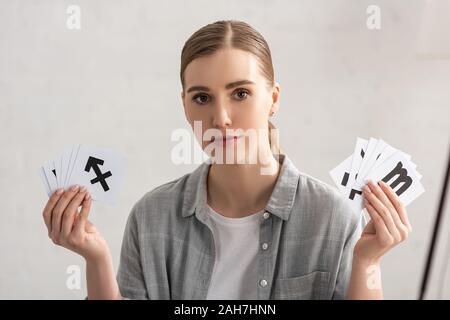 Attraktive Astrologen auf Kamera und zeigen Karten mit Sternzeichen Stockfoto