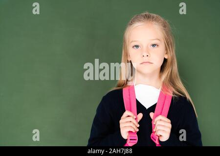 Traurig Schulmädchen auf Kamera beim Stehen in der Nähe von Green Kreidetafel Stockfoto