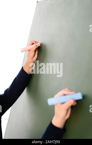 7/8-Ansicht von zwei multikulturelle Schülerinnen schreiben auf der Schiefertafel isoliert auf weißem Stockfoto