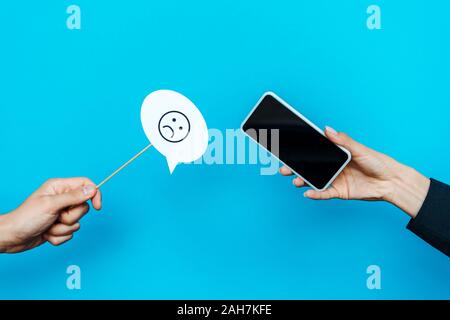 Kiew, Ukraine - August 5, 2019: Frau mit Stick mit traurigem Gesicht in der Nähe von Mann smartphone Holding mit leeren Bildschirm auf Blau Stockfoto