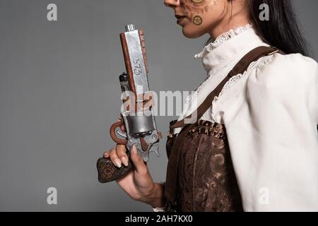 7/8-Ansicht von steampunk Frau mit Vintage Pistole isoliert auf Grau Stockfoto