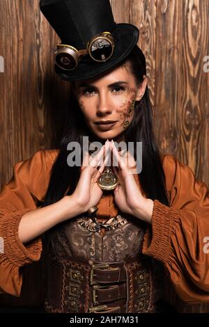 Attraktive Frau mit steampunk Make-up berühren Medaillon auf Holz- Stockfoto