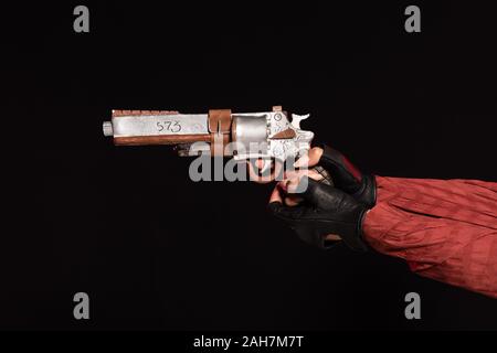 7/8-Ansicht der jungen Frau in Leder Handschuhe holding Pistole isoliert auf Schwarz Stockfoto